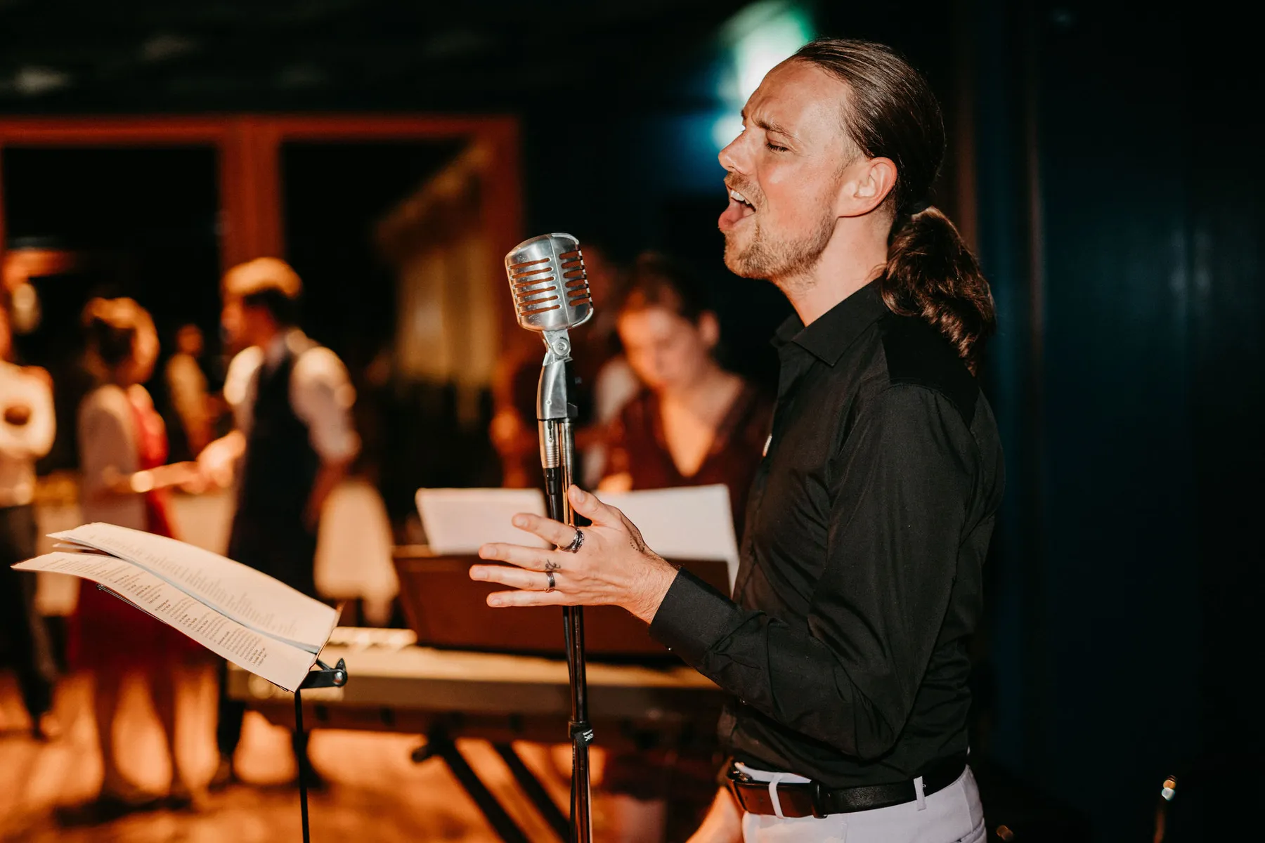 Maik singt an einem Mikrofon, vor ihm liegen aufgeschlagene Noten.