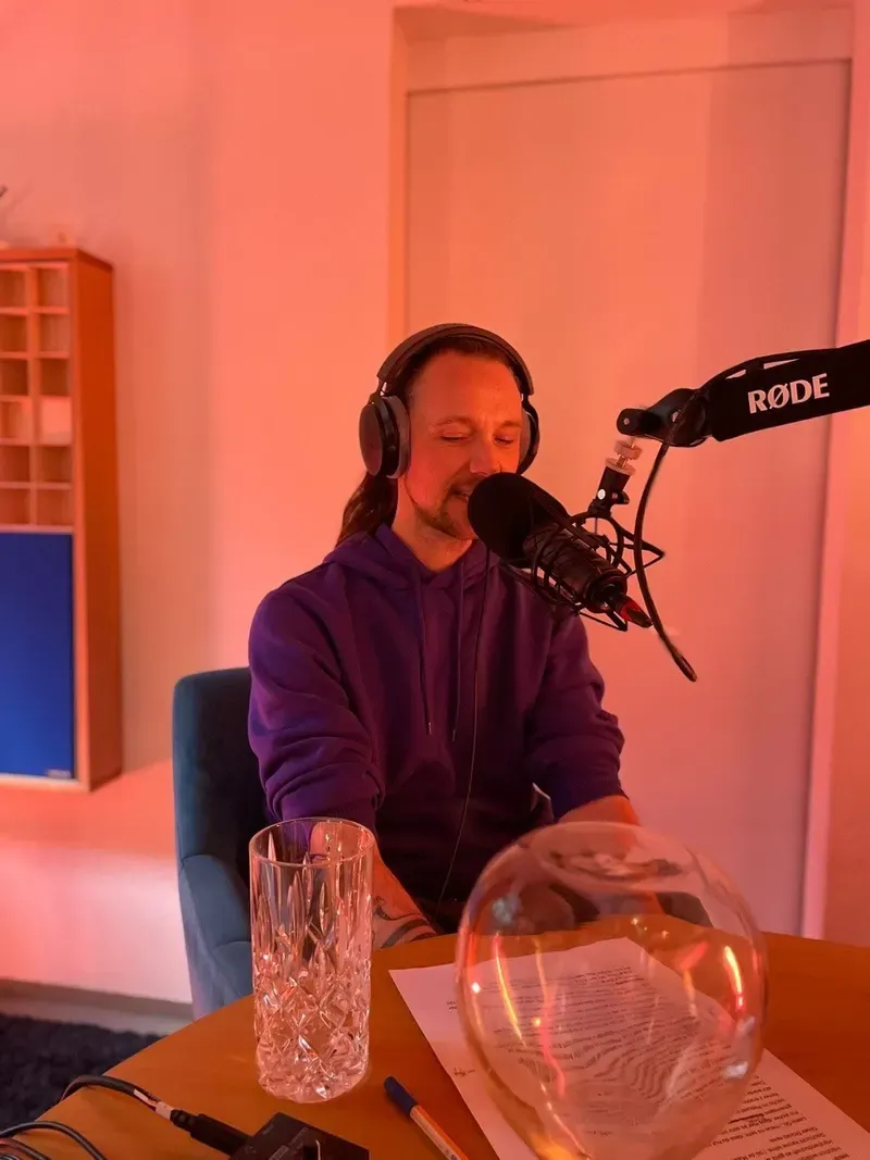 Maik mit Kopfhörern am Mikrofon am Aufnahmetisch im Tonstudio.
