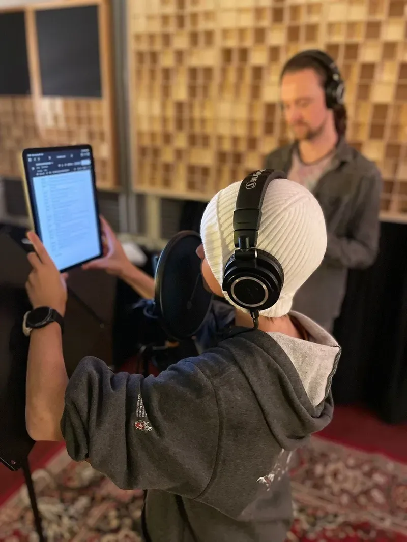 Bei der Hörspielaufnahme: Paco von Wyss am Mikrofon mit einem Tablet, Maik mit Kopfhörern im Hintergrund.