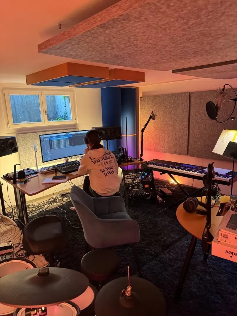 Blick ins Tonstudio mit Aufnahmeplatz, Instrumenten und Maik bei der Arbeit am Computer.